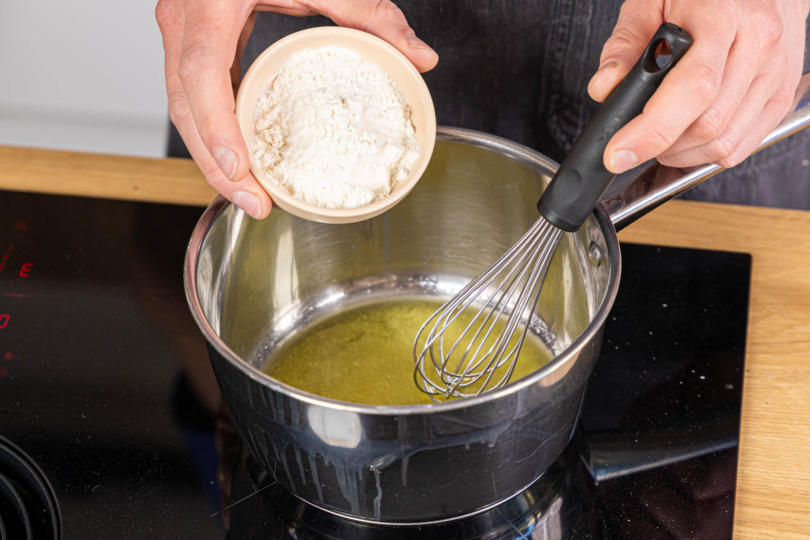 Mehl zur geschmolzenen Butter in den Topf geben