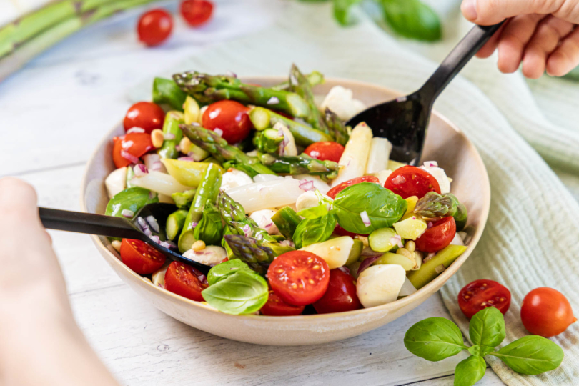 Spargelsalat mit Tomaten und Mozzarella mit Salat besteck entnehmen