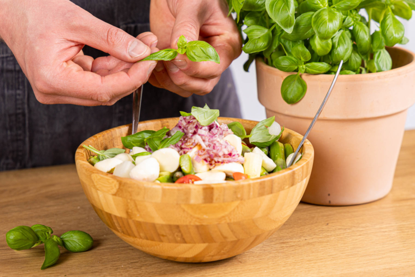 Basilikum über den Spargelsalat mit Tomaten und Mozzarella zupfen