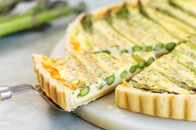 Stück Spargelquiche mit grünem Spargel herausheben