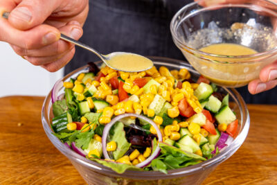 Dressing über Wildkräutersalat geben