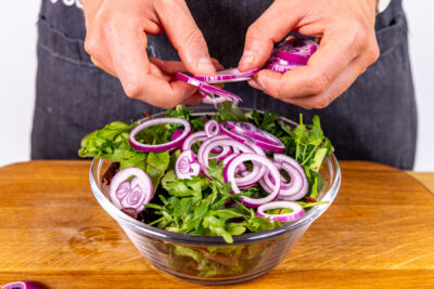 Zwiebelringe über Salat geben