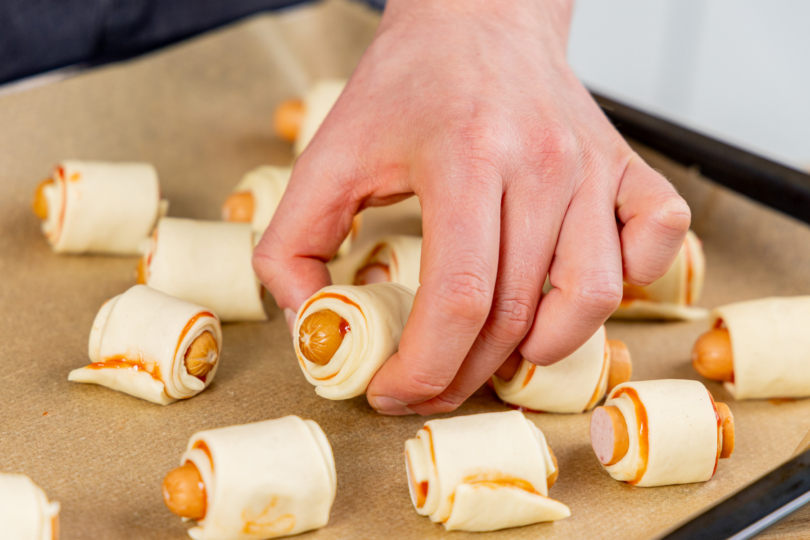 Würstchen im Pizzateig aufs Backblech legen