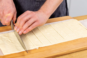 Pizzateig in Streifen schneiden