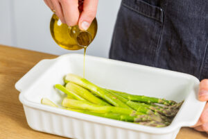 Olivenöl über Spargel geben