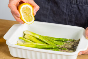 Zitronensaft über Spargel geben