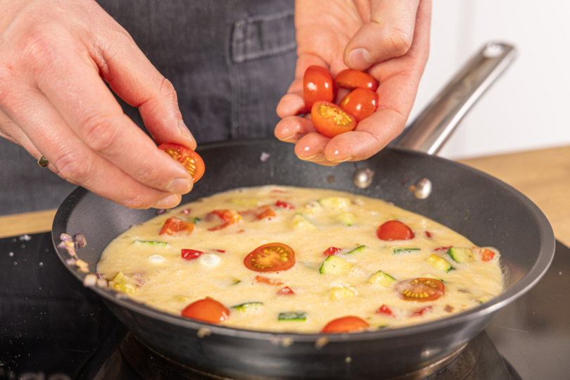 Tomaten auf der Frittata verteilen
