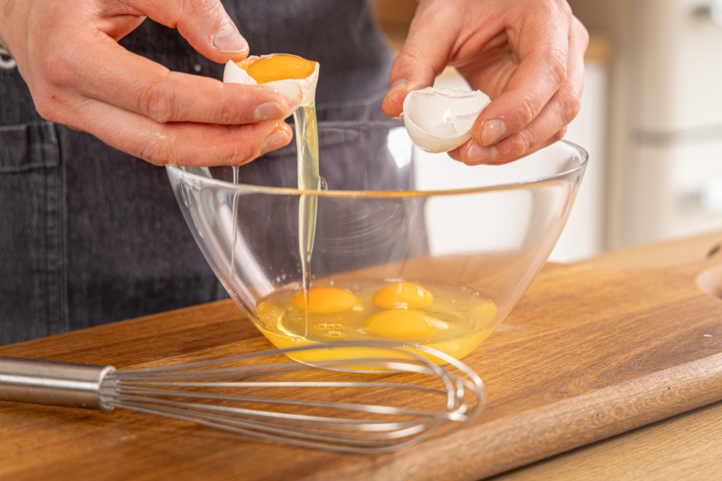 Eier in eine Schüssel schlagen