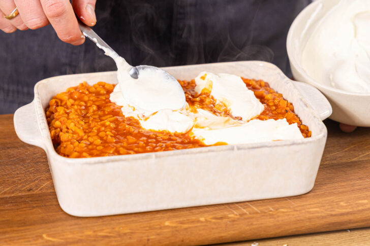 Crème fraîche auf die Linsenlasagne geben