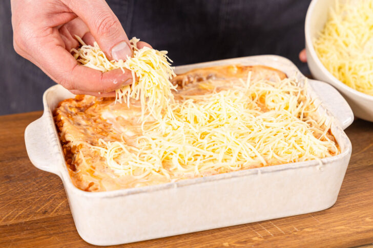 Linsenlasagnbe mit Käse bestreuen