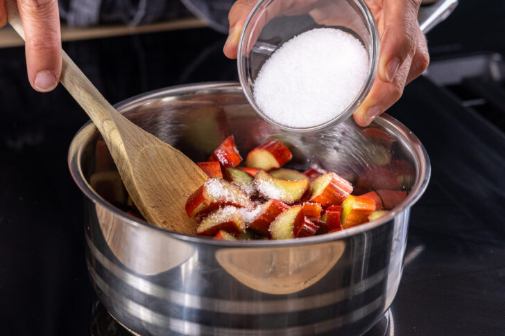 Zucker zum Rhabarber in den Topf geben, für Rhabarber-Cheesecake-Dessert im Glas