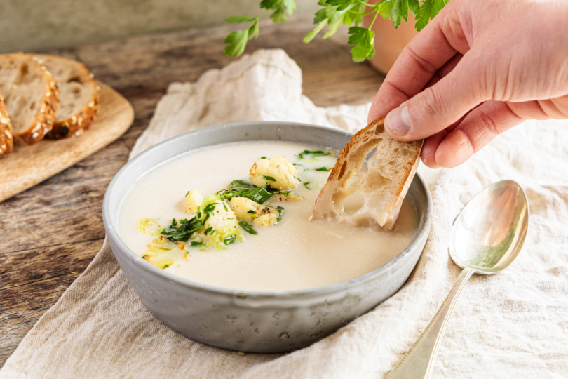 Brot in vegane Blumenkohlsuppe tunken