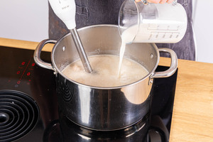 Hafersahne zur veganen Blumenkohlcremesuppe gießen