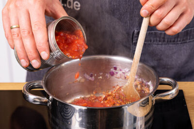 gehackte Tomaten dazugeben und köcheln lassen