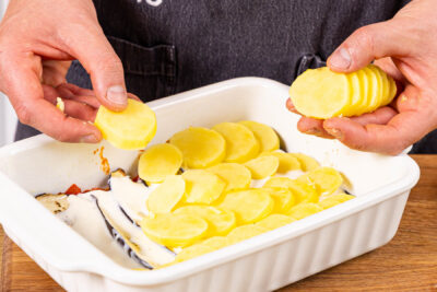Kartoffelscheiben auf die Bechamel schichten