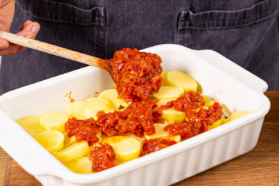 Tomatensauce auf Kartoffelscheiben verteilen