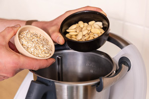Haferflocken, Cashewkerne und Mandeln in den Mixtopf geben