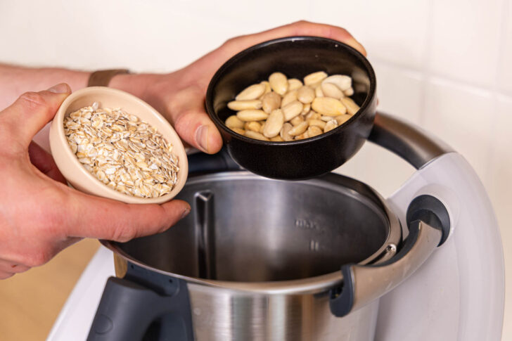 Haferflocken, Cashewkerne und Mandeln in den Mixtopf geben