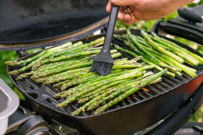 grünen Spargel auf dem Grill mit Öl einstreichen