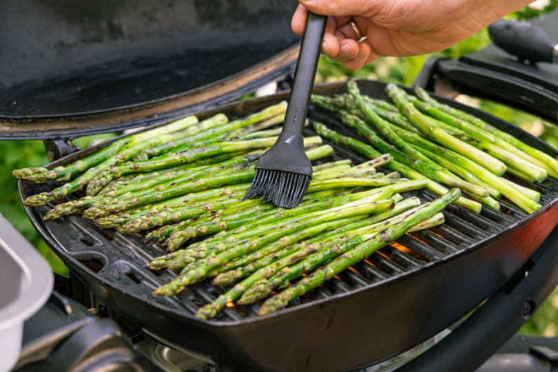 grünen Spargel auf dem Grill mit Öl einstreichen