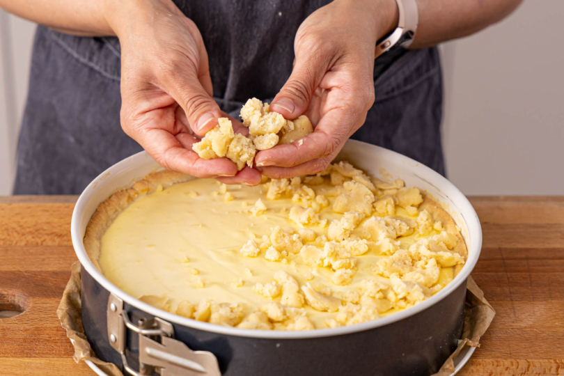 Streusel auf dem vorgebackenen Kuchen verteilen