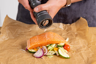 Lachs auf Gemüsebett würzen