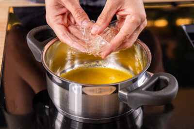 Gelatine in dem Topf zum Pfirsichpüree geben