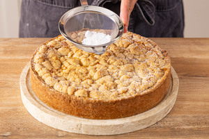 Apfelmuskuchen mit Streuseln mit Puderzucker bestreuen