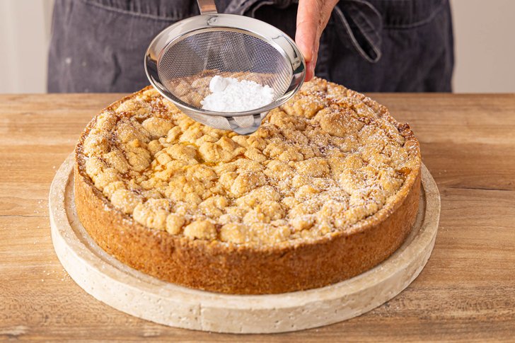 Apfelmuskuchen mit Streuseln mit Puderzucker bestreuen