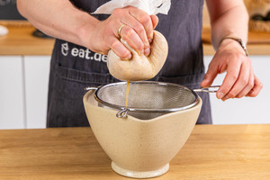 Apfelmasse im Passiertuch mit der Hand auspressen