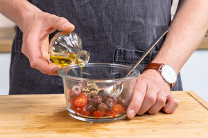 Öl zu Tomaten und Oliven geben
