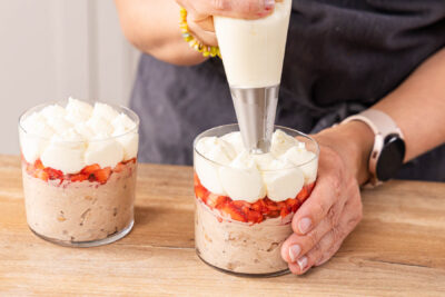 Creme auf das Erdbeer-Bueno-Dessert spritzen