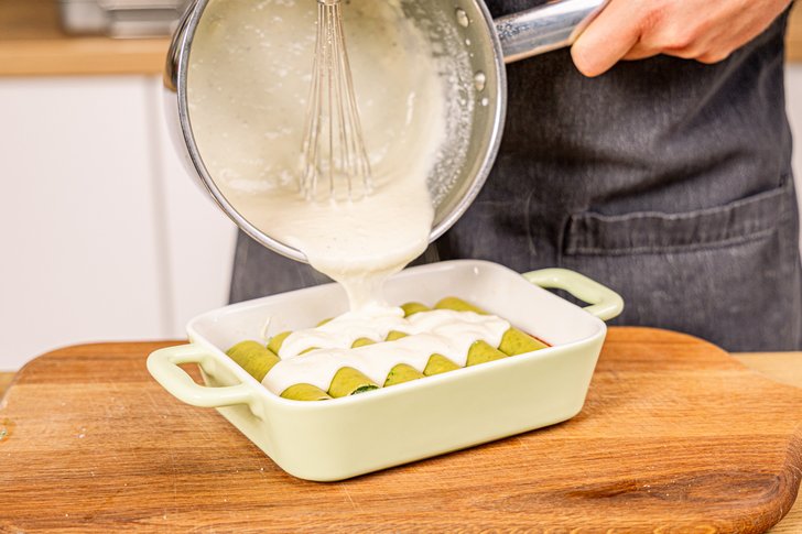 Béchamelsauce auf den Cannelloni verteilen