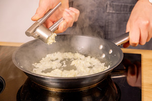 Knoblauch in die Pfanne pressen