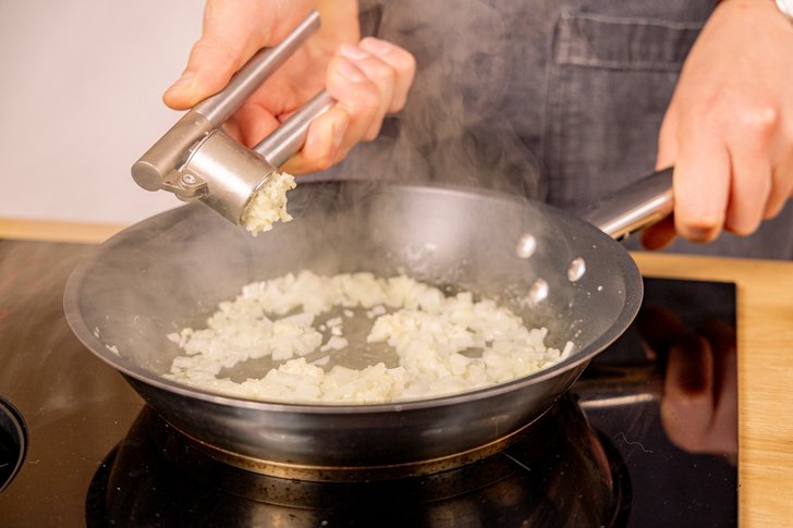 Knoblauch in die Pfanne pressen
