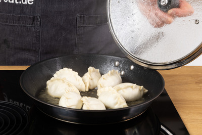 Dumplinge garen in der Pfanne mit offenen Deckel