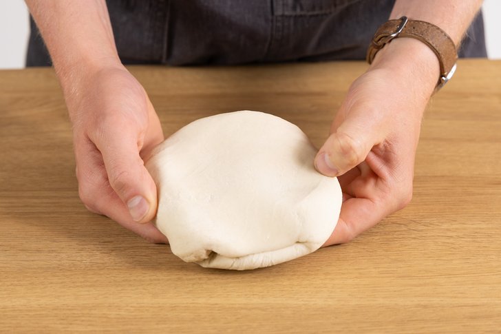 Dumplingteig nach Ruhezeit in den Händen haltend