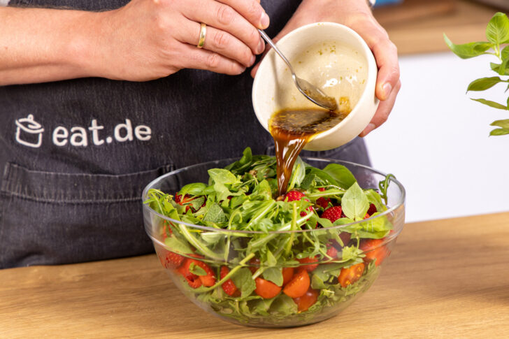 Dressing über den Salat geben