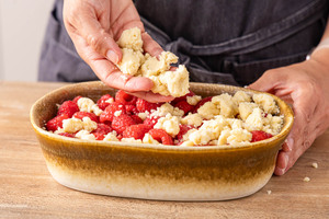 Streusel über Himbeer Crumble streuen