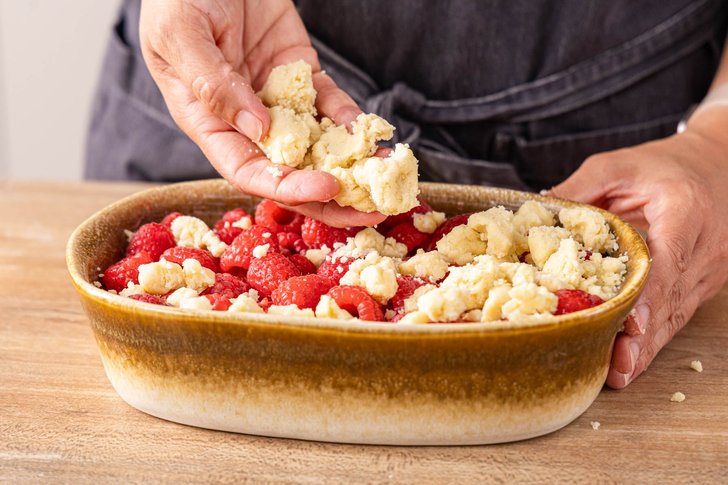 Streusel über Himbeer Crumble streuen