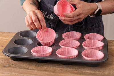 Muffinförmchen ins Muffinblech geben