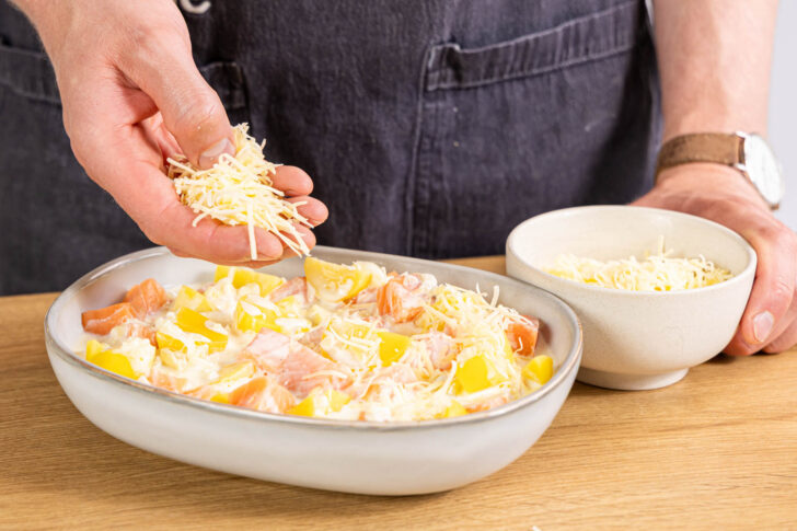 Lachs-Kartoffel-Auflauf mit Käse bestreuen
