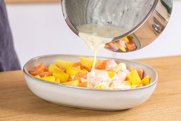 Sauce auf den Lachs-Kartoffel-Auflauf gießen