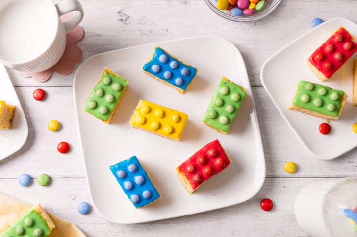 Bunter Legokuchen mit Zuckerguss und Schokolinsen auf einem Teller