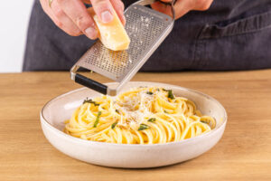 Parmesan auf Pasta mit Salbei und Zitrone reiben