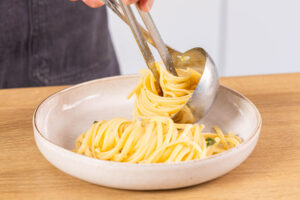 Pasta mit Salbei und Zitrone auf Teller drapieren