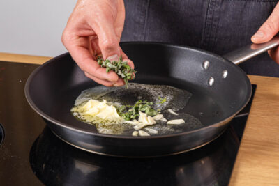 Salbei zur Butter und Knoblauch in die Pfanne geben