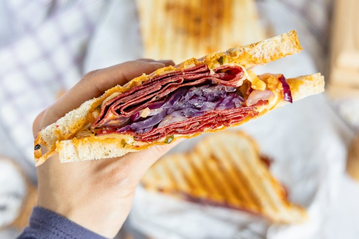 Pastrami Sandwich vom Kontaktgrill in der Hand