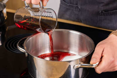 Kirschsaft zum Zucker in den Topf gießen