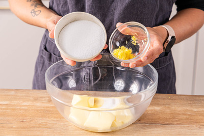 Zucker und Zitronenschalenabrieb zur Butter geben